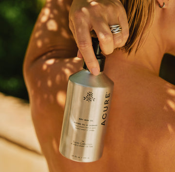 Person holding a bottle of Acure body wash with a blurred natural background